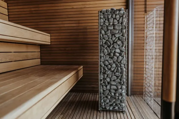 Sauna room with stacked stone heater and wooden benches
