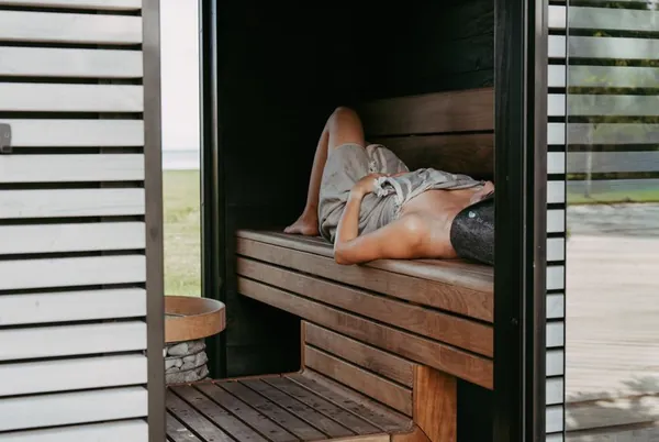 Woman lying on a bench inside a modern sauna