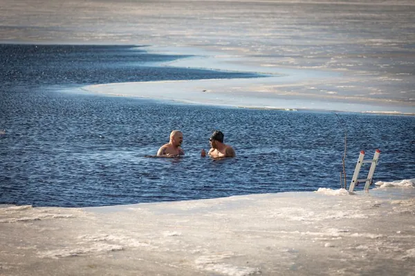 Two people swimming in icy open water