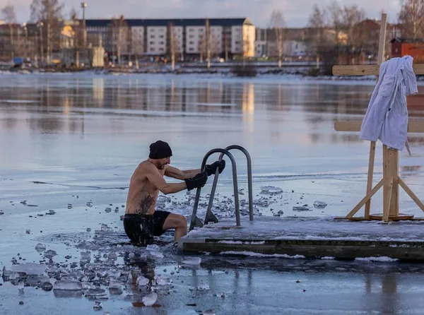 Man climbing out of an ice hole after a cold plunge