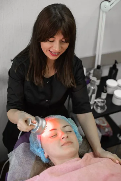 Practitioner giving a red light therapy facial treatment